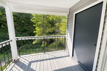 The view from the balcony of a home with a large screen door and a yard